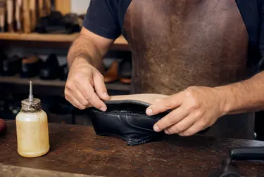 Profissional reformando uma bolsa de couro.